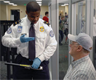 A TSA Officer screening a passenger A TSA Officer screening a passenger