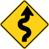A USA road sign indicating a winding road ahead, with an initial curve to the right A USA road sign indicating a winding road ahead, with an initial curve to the right