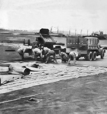 Soldiers of IX Engineering Command, U.S. Army Air Force, putting down a Pierced Steel Planking (PSP) Runway at an Advanced Landing Ground under construction somewhere in France following the Normandy Landings of World War II Soldiers of IX Engineering Command, U.S. Army Air Force, putting down a Pierced Steel Planking (PSP) Runway at an Advanced Landing Ground under construction somewhere in France following the Normandy Landings of World War II